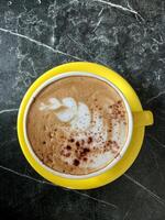 cup of yellow glass cappuccino coffee on the table. photo