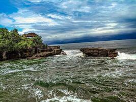 the ocean is surrounded by rocks and a house photo
