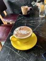 cup of yellow glass cappuccino coffee on the table. photo