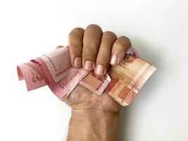 hand holding a stack of one hundred thousand rupiah notes. photo