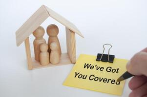 We have got you covered text written on yellow notepad with wooden family dolls figure background photo