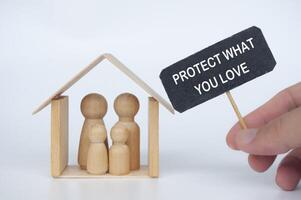 Protect what you love text on black signage with family figure background. Insurance coverage concept photo