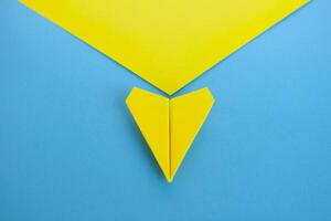 Close up top view view of yellow paper airplane flying along the route on blue background photo