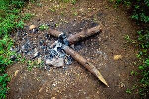A dying campfire surrounded by ash and rocks in a forest clearing. photo