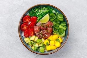 Healthy tuna poke bowl overhead top view. Poke is a traditional Hawaiian dish influenced by japanese and asian cuisine. Ahi poke is made of raw tuna chunks tossed over rice and topped with vegetables. photo