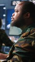 Vertical Army operative in command center analyzing surveillance data during global warfare. Intelligence agent in base of operations completes mission during World War 3 geopolitical operation, camera A video