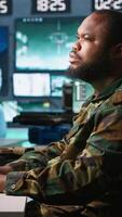 Vertical Officer in command center helped by colleague to plan, analyze and gather information on enemy troops. Team of agents in base of operations doing assessment of adversaries vulnerabilities, camera A video