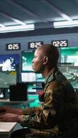 Vertical Intelligence operative in military base doing surveillance with digital radar equipment, operating missile systems. African american man monitoring army HQ CCTV for any unauthorized activity, camera B video