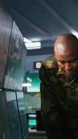 Vertical Team of soldiers looking at screens in command center housing operational missile defense system designed to intercept ballistic rockets. Tracking equipment operators using radar systems, camera B video