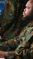 Vertical Military soldier in mission command post overseeing national safety operations, talking on phone. African american army expert in telephone call in monitoring room, camera A video