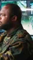 Vertical Counterintelligence specialist in military HQ base gathering information on enemy troops. African american agent in base of operations doing assessment of enemy vulnerabilities, tracking, camera A video