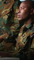 Vertical Soldier in military HQ base doing brainstorming with coworker, gathering information on enemy troops. Teamworking officers using tracking software to do assessment of enemy vulnerabilities, camera A video