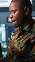 Vertical Teamworking military agents look at intel folder files on enemy battle formation. Intelligence corps coworkers read mission case documents to collect data on opponents strategy, camera A video