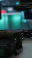 Vertical Weapons on table in secure room in army governmental facility operating as military command post and surveillance monitoring center. Extreme close up of guns in empty military base of operations video