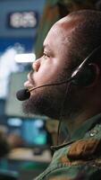 Vertical Army telecommunication systems operator using radio and satellite gear, providing combat support. Military dispatcher managing communications networks, looking at screens, camera A video