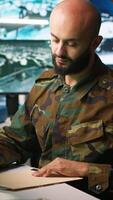 Vertical Tired military officer receiving intel folder on enemy, feeling fatigued. Overworked army specialist feeling exhausted while reading mission case file to collect data on opponents strategy, camera A video