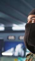 Vertical Portrait of terrorist loading gun, attacking enemy command center. Close up of masked insurgent reloading pistol during enemy base assault hijacking in guerilla warfare armed conflict, camera B video