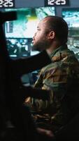 Vertical Army expert working in governmental facility operating surveillance tech, evaluating target data. Soldier doing job in HQ base of operations, engage enemy forces, camera A video