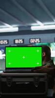 Vertical Soldier using tracking software on green screen laptop to gain info against enemies. Army expert using chroma key notebook to gain intel helping troops, coordinating mission activities, camera B video