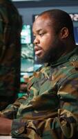 Vertical Military agent working overtime in control room to analyze aerial reconnaissance data, feeling tired. Exhausted intelligence corps agent controlling drones, suffering from headache, camera B video