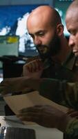 Vertical Army officers doing brainstorming in command center, looking at intel folder files. Intelligence corps experts read mission case paperwork to be informed on data on opponents strategy, camera A video