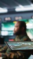 Vertical Army operative using tablet in command center housing operational missile defense system designed to intercept ballistic rockets. Close up of expert using tracking software on device, camera B video