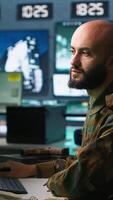 Vertical Man looking at screens in military HQ base housing operational missile defense system designed to intercept ballistic rockets. Special forces expert using tracking gear and radar systems, camera A video