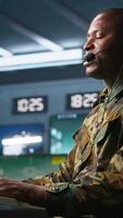 Vertical Army specialist working in war room operating surveillance tech, evaluating target data, talking in voice call. Dispatcher keeping in touch with allied troops engaging enemy forces, camera A video