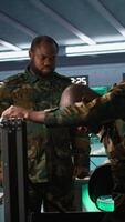 Vertical Military officers working together to check guns in command post, ensuring bullets and supplies are working properly. Team of soldiers holding pistol and rifles, managing combat load gear, camera B video