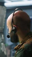 Vertical Army telecommunication systems operator using radio and satellite equipment. Middle Eastern military dispatcher managing communications networks, looking at screens, camera A video