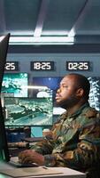 Vertical Army expert working in governmental facility operating surveillance tech, evaluating target data. Soldier doing job in HQ base of operations, engage enemy forces, camera B video