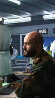 Vertical Man looking at screens in military HQ base housing operational missile defense system designed to intercept ballistic rockets. Special forces expert using tracking gear and radar systems, camera B video