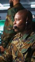 Vertical Army telecommunication systems operator using radio gear, providing combat support, doing patriotic duty. African american military dispatcher managing communications networks, camera B video