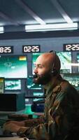 Vertical Soldier solving tasks in military HQ base, gathering information on enemy troops. Middle Eastern agent in base of operations doing assessment of enemy vulnerabilities, tracking, camera B video