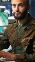 Vertical Special forces military agent working in control room, analyzing aerial reconnaissance data. Close up of intelligence corps expert controlling drones attacking strategic targets, camera B video