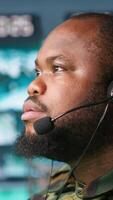 Vertical Military dispatcher relays info from army intelligence analysts to troops on front lines, close up shot. Radio communications operator wearing uniform talking in headset mic, camera A video