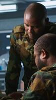 Vertical Military officers look at intel folder files on enemy battle formation, comparing with radar images. Army specialists looking at mission case file and equipment screens, camera A video