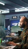 Vertical Military agent working in control room, analyzing aerial reconnaissance data. Intelligence corps agent controlling drones attacking strategic targets, camera B video