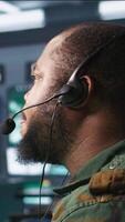 Vertical Military dispatcher using headphones microphone, offering information to commanders fighting on front lines. Army expert providing intel for troops in base of operations, camera B video