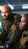 Vertical Air force officers performing tactical level reconnaissance in command post, looking at monitors. Military soldiers using radar devices to look at assault zones on displays, camera B video
