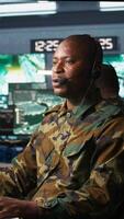 Vertical Army specialist working in war room operating surveillance tech, evaluating target data, talking in voice call. Dispatcher keeping in touch with allied troops engaging enemy forces, camera B video
