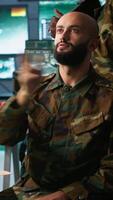 Vertical Military agent using augmented reality tech in control room, analyzing aerial reconnaissance data. Intelligence corps expert controlling drones attacking strategic targets using AR hologram, camera A video