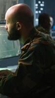 Vertical Army soldier looking at chroma key screens in command center housing operational missile defense system designed to intercept ballistic rockets. Specialist using mockup tracking gear, camera A video
