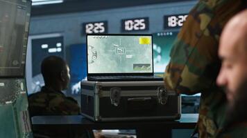 Air force combat control agent performing tactical level surveillance in war room using laptop. Military expert in base of operations using radar on notebook to look at assault zones, camera A video