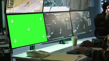 Air force officer performing tactical level surveillance in command room using mockup screen. Military specialist using radar on chroma key gear to look at assault zones, camera A video