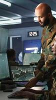 Vertical Army colleagues looking at screens in command center housing operational missile defense system designed to intercept ballistic rockets. Experts using tracking gear and radar systems, camera B video