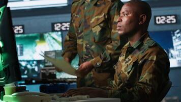 Soldier in military HQ base doing brainstorming with coworker, gathering information on enemy troops. Teamworking officers using tracking software to do assessment of enemy vulnerabilities, camera A video