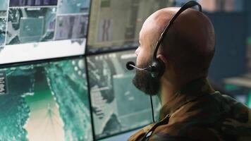 Army specialist working in war room operating surveillance tech, evaluating target data. Close up on dispatcher doing job in HQ base of operations, engaging enemy forces, camera A video