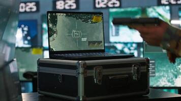 Air force officer performing tactical level surveillance in command room using laptop. Close up of military specialist in base of operations using radar on notebook to look at assault zones, camera A video