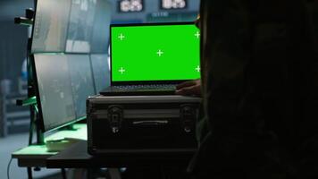 Army specialist working in war room operating surveillance tech, evaluating target data on isolated screen laptop. Soldier engaging enemy forces using chroma key notebook, camera A video